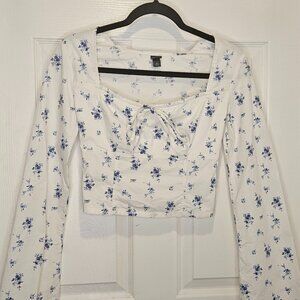 White long sleeve blouse with blue flowers cropped at waist.